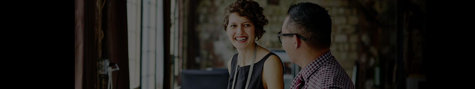 Two coworkers laughing together while discussing something