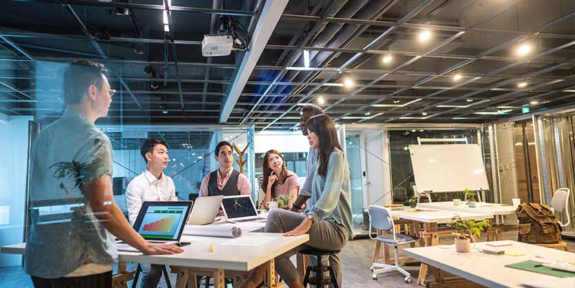 Group of young, modern people sitting on business meeting in modern coworking space and suggesting ideas for the best business strategy