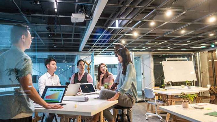 Group of young, modern people sitting on business meeting in modern coworking space and suggesting ideas for the best business strategy