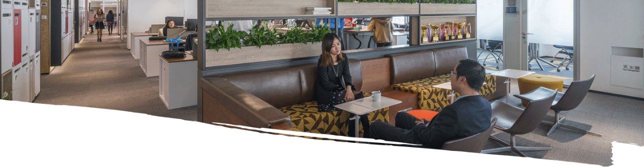 A female and male employee sitting in front of each other in office break area and doing conversation